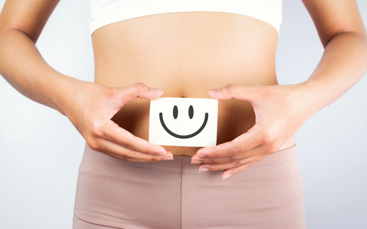 wooden block with a smile on it held in front of a flat stomach
